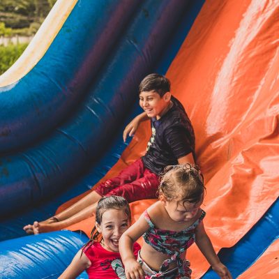 a group of children sitting on top of a blue and orange inflatable slide