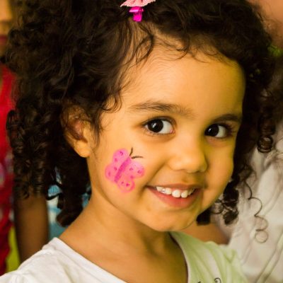 girl in white crew neck shirt with pink and white polka dots on her face